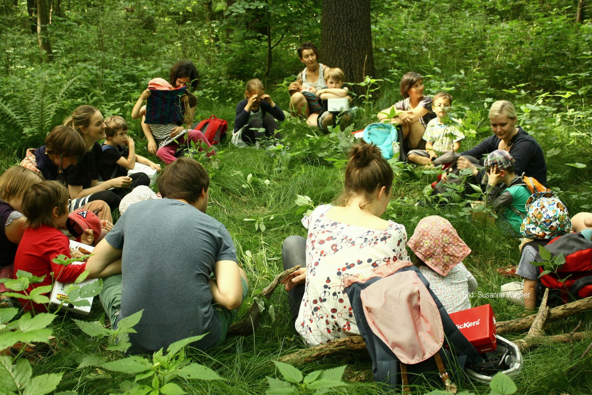 Kinder und Eltern im Sitzkreis auf Waldboden
