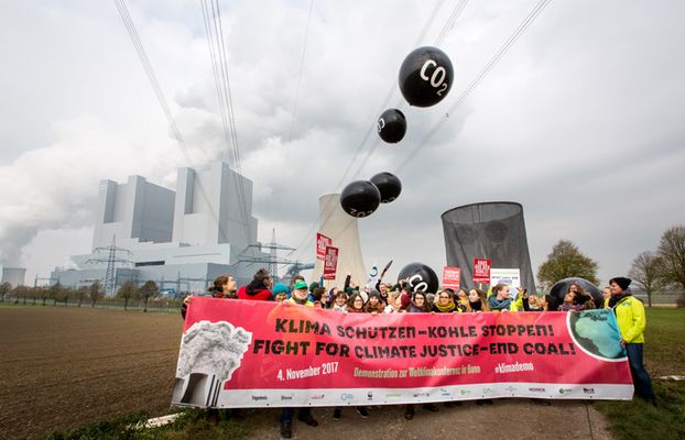 Demonstrierende vor Kohlekraftwerk mit Banner auf dem steht: "Klima schützen, Kohle stoppen!"