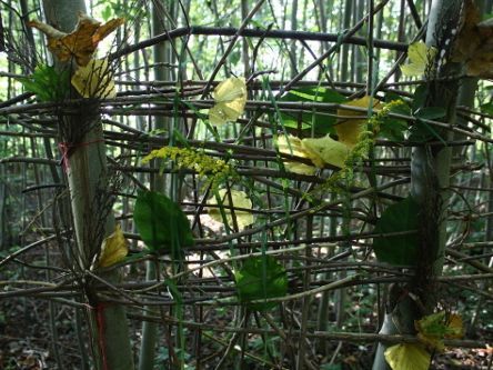 Geflochtenes Kunstwerk von Kindern aus Zweigen und Blättern zwischen Stämmen