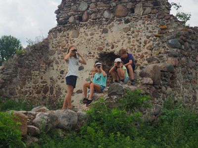 Kinder mit Ferngläsern auf Mauer einer Ruine