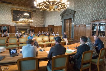 Blick vom Podium auf ein prall gefülltes Publikum im prächtigen Ratsplenarsaal.