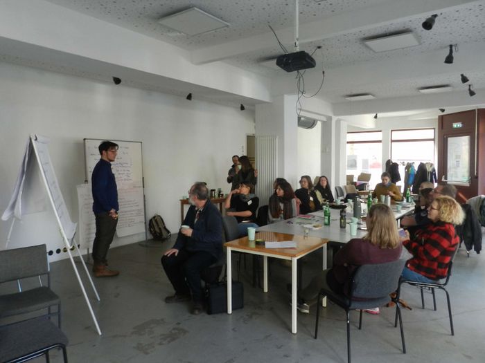 Präsentation, Vortragender steht vor Whiteboard, Zuhörende am Tisch