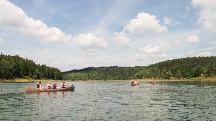 Ruderbote auf dem See, rundherum Hügel mit Wald