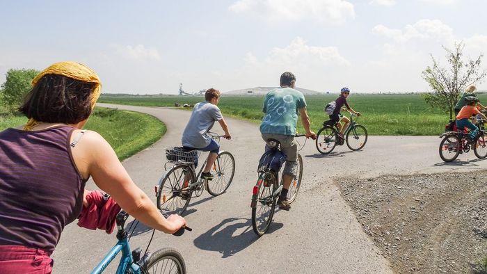 Ein Gruppe von Menschen, die im Grünen auf den Feldern Rad fahren.