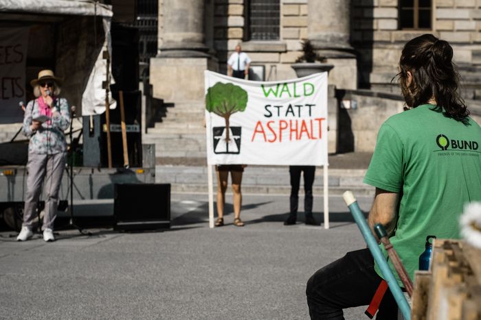 Mensch in grünem Shirt von hinten zu sehen. Er schaut auf ein beschriftetes Banner.