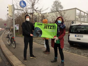 zwei Personen mit Maske halten ein Banner mit der Aufschrift "Klimaschutz Jetzt"