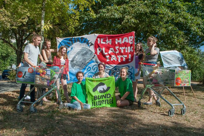 Gruppenfoto der BUNDjugend Leipzig mit Aktionstransparent zur Plastic Attack unter Bäumen.
