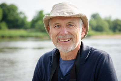 Porträt Ernst Paul Dörfler, vor einem Fluss, er lächelt und trägt einen Strohhut